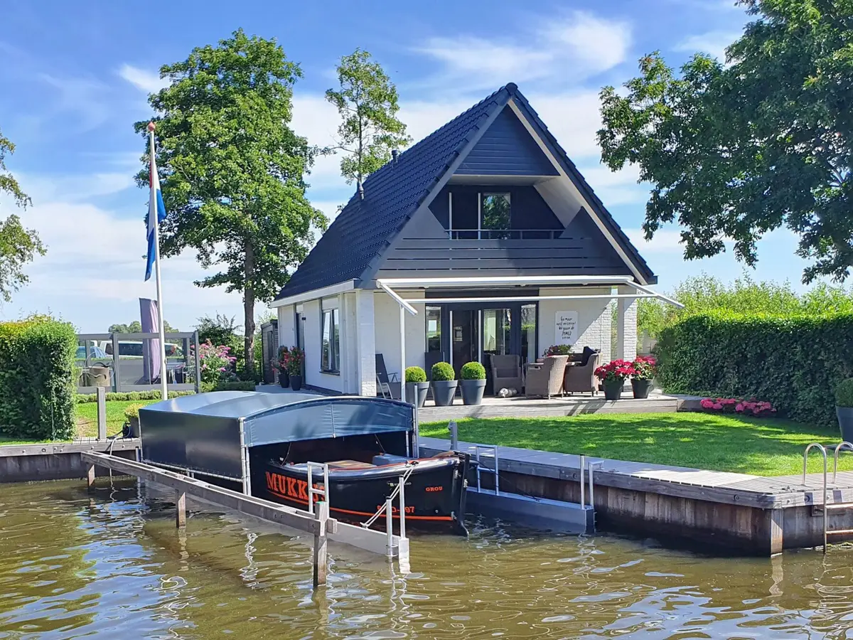 Drijvend boothuis met sloep aan de kade van een woning aan het water